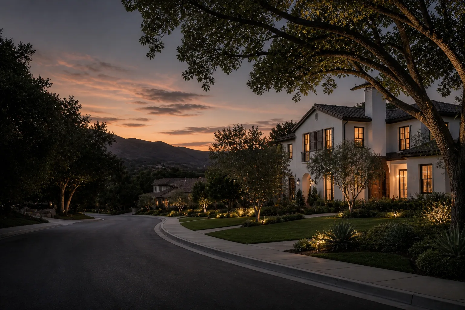 A premium residential neighborhood combining mature tree canopy, foothill views, and a warm modern home at dusk